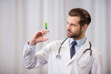 Doktor elinde şırınga tutuyor.