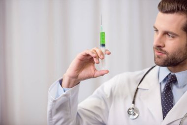 Doktor elinde şırınga tutuyor.