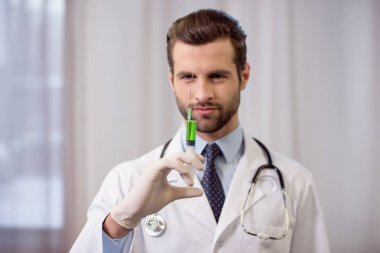 Doktor elinde şırınga tutuyor.