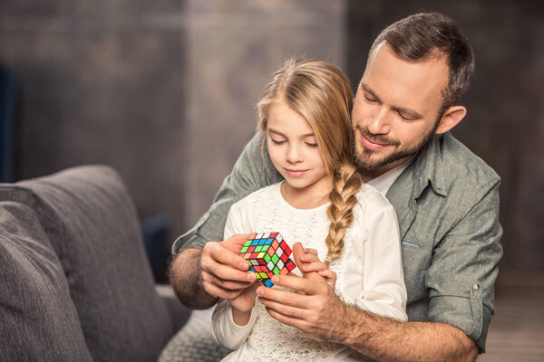 Father and daughter playing with rubik's cube