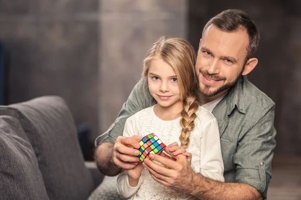 Отец и дочь играют с кубиком Рубика — стоковое фото