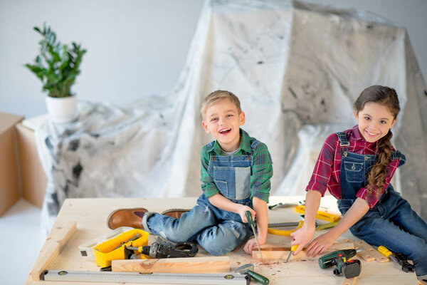 Kids sawing wooden plank
