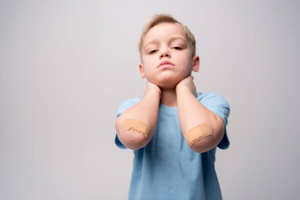Little boy with patches on elbows 