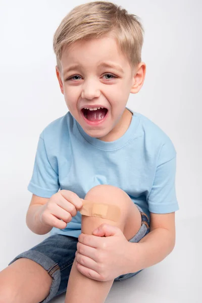 Niño pequeño con parche en la rodilla —  Fotos de Stock