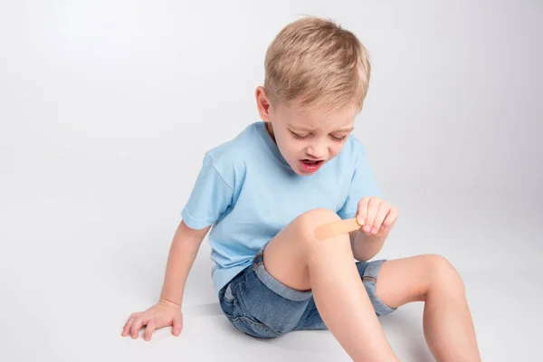 Niño pequeño con parche en la rodilla — Foto de Stock