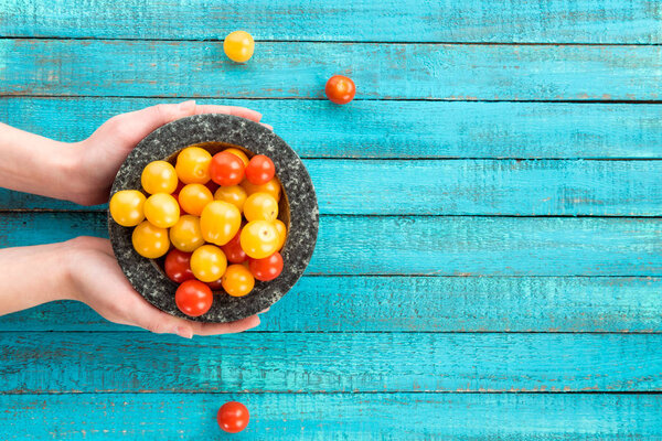 hands holding cherry-tomatoes