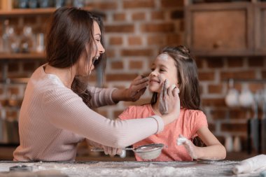 Mother and daughter sifting flour clipart