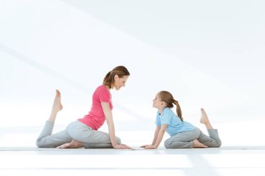 Anne ve kızı yoga yapıyor.
