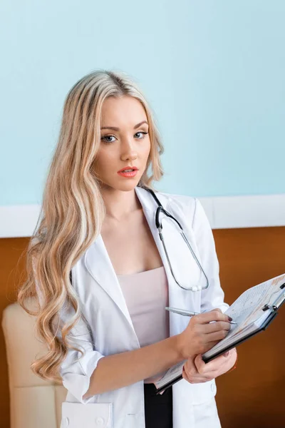 Hermoso doctor escribiendo en bloc de notas — Foto de Stock