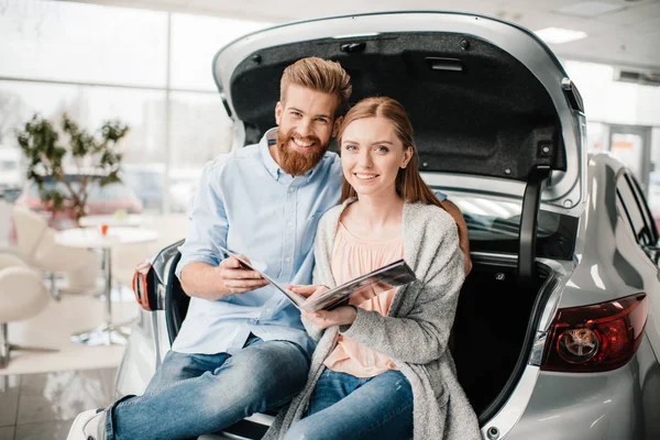 Couple with catalog in dealership salon — Stock Photo, Image