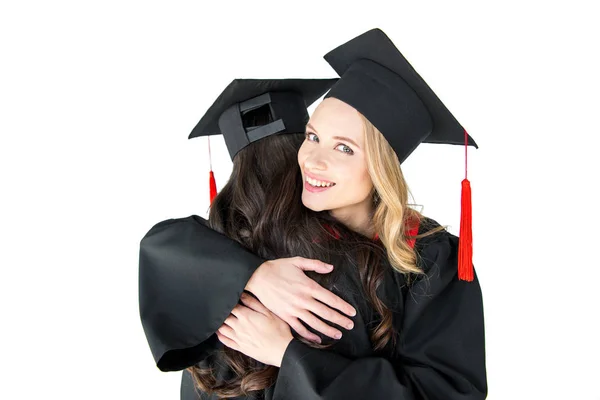 Estudantes em bonés de formatura abraçando — Fotografia de Stock