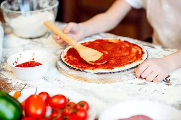 Girl putting sauce on dough — Stock Photo, Image