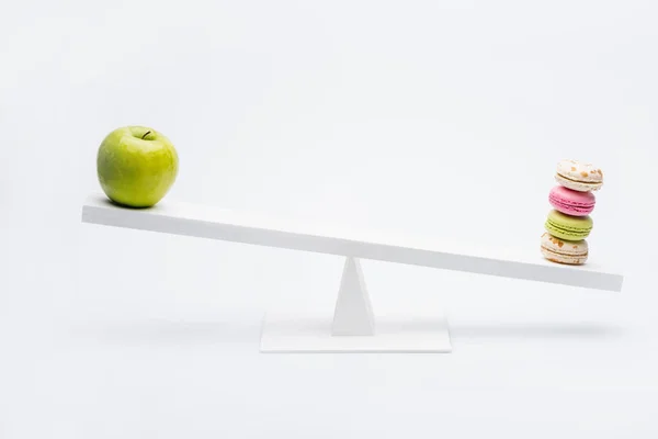 Apple and macarons on seesaw — Stock Photo, Image