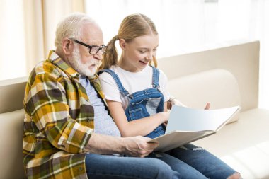 Grandfather with girl reading book clipart