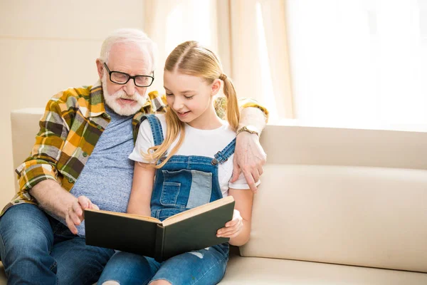 Farfar med tjej läser bok — Stockfoto