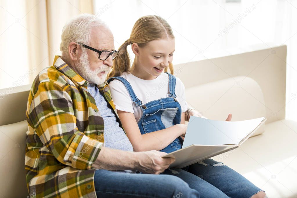 Grandfather with girl reading book