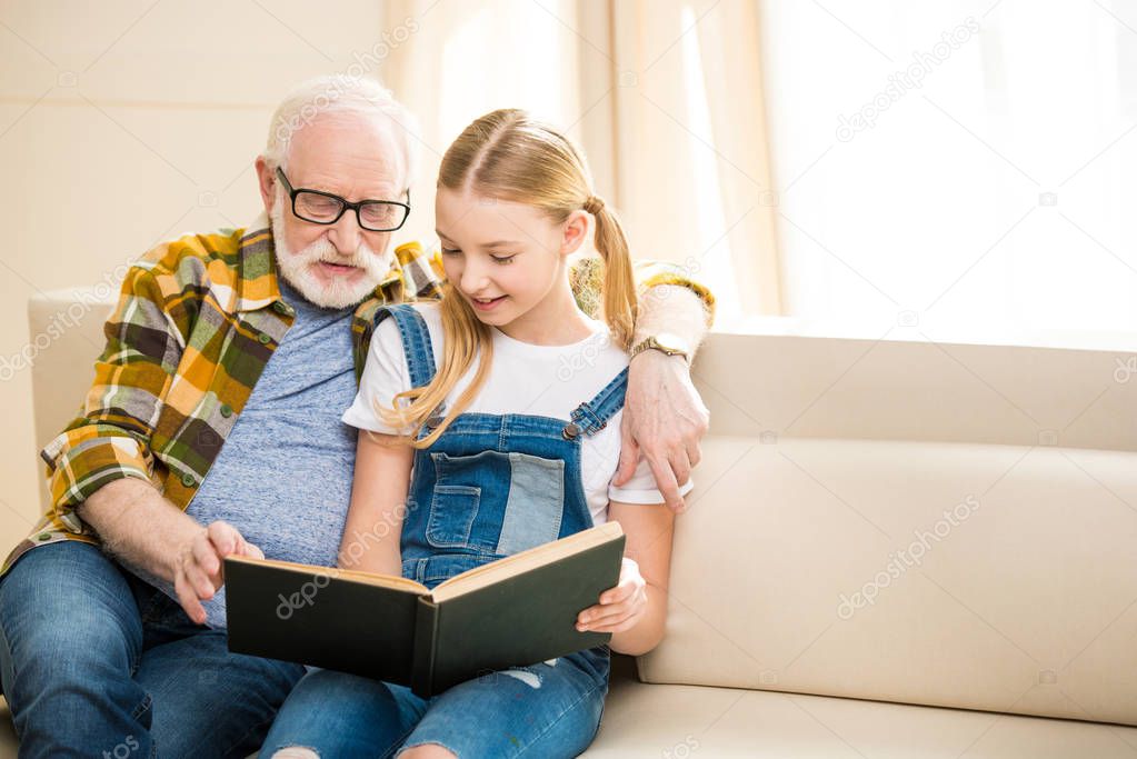 Grandfather with girl reading book