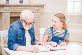 Großvater mit Mädchen liest Buch