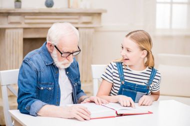 Grandfather with girl reading book clipart