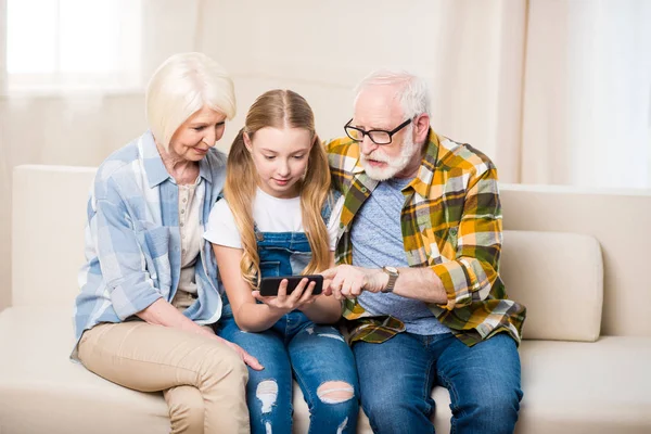 Lány a nagyszülők használ smartphone — Stock Fotó