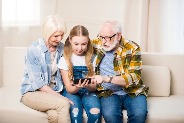 Meisje met grootouders met smartphone — Stockfoto