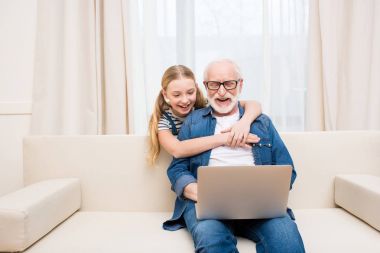 Girl with grandfather using laptop clipart