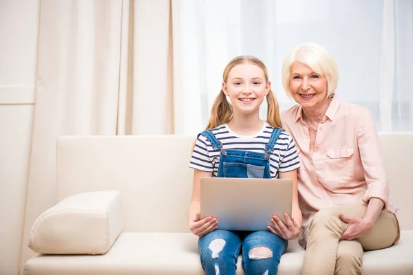 Flicka med mormor använder laptop — Stockfoto
