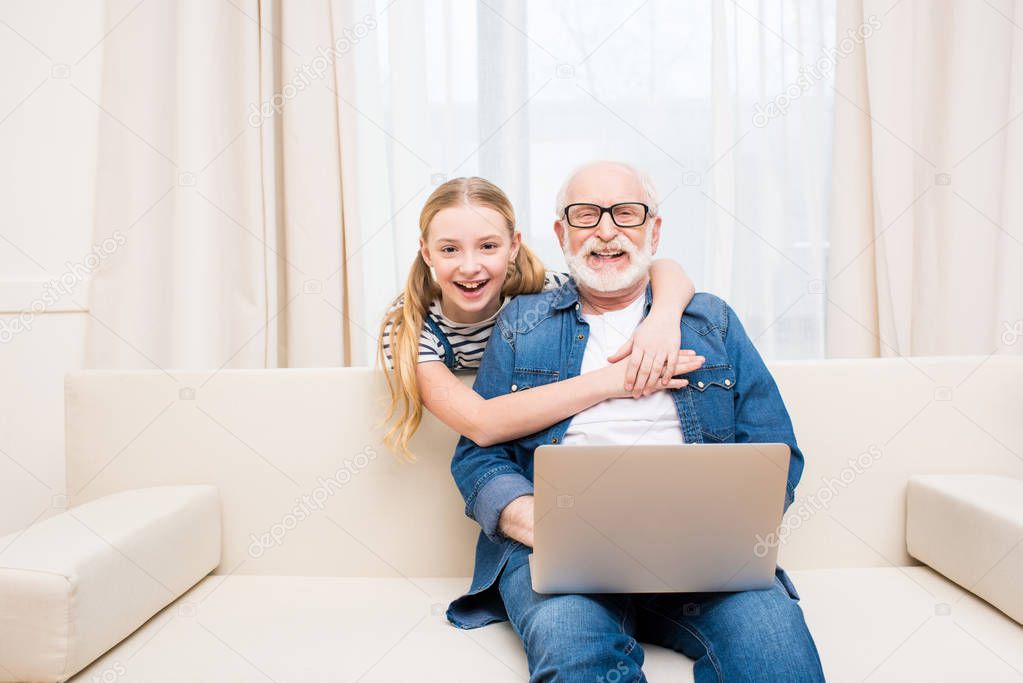 Girl with grandfather using laptop