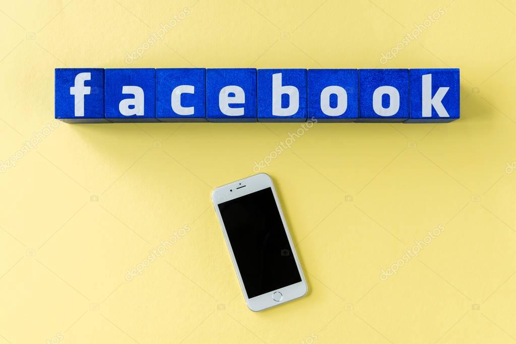 Facebook logo made from blue cubes with smartphone on yellow surface