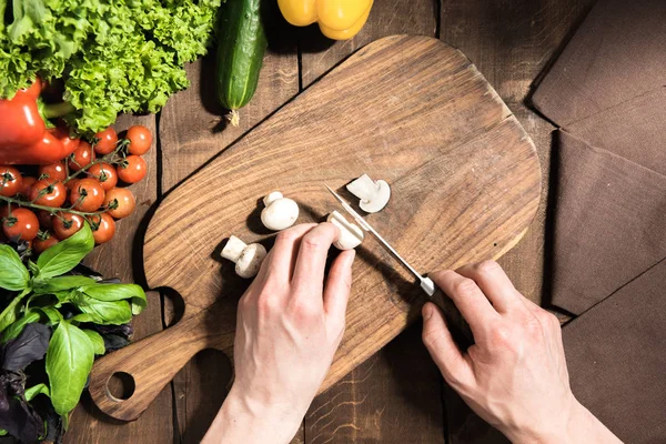 Hands cutting mushrooms on chopping board — Stock Photo, Image