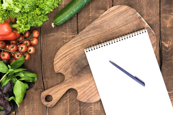 Notepad with raw vegetables on table — Stock Photo, Image