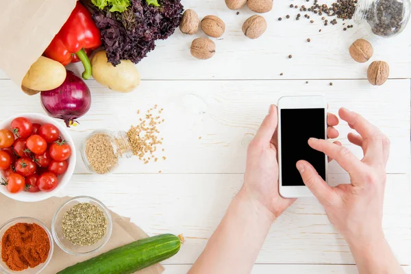 Особа, яка використовує смартфон під час приготування їжі — стокове фото