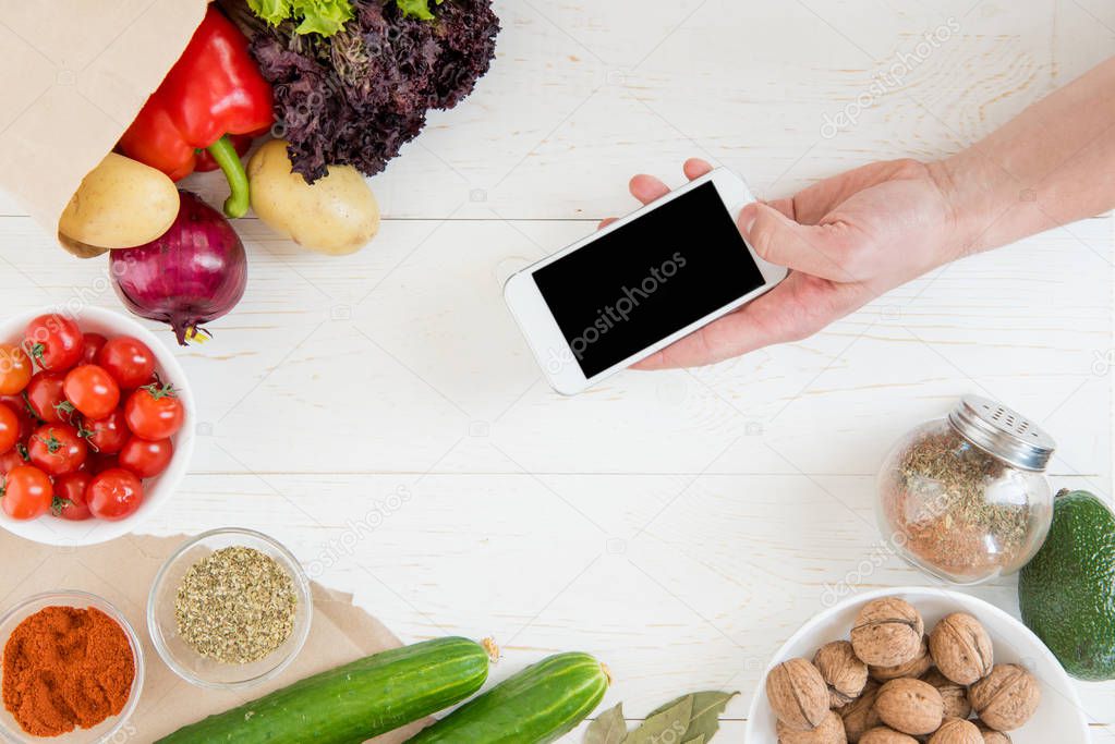 Smartphone over table with vegetables  