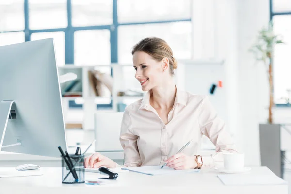 Glimlachende zakenvrouw werken op de computer op kantoor — Stockfoto