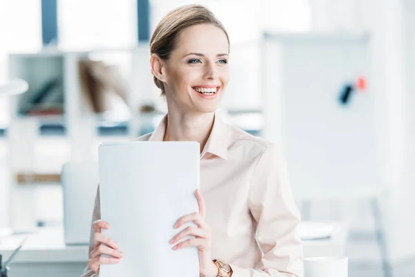 Усміхнена бізнес-леді тримає документи в офісі — стокове фото