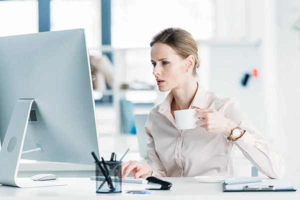 Businesswoman working on computer and drinking coffee — Stock Photo, Image