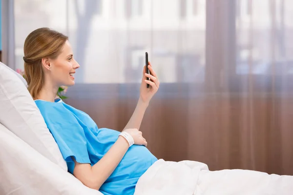 Беременная женщина со смартфоном — стоковое фото