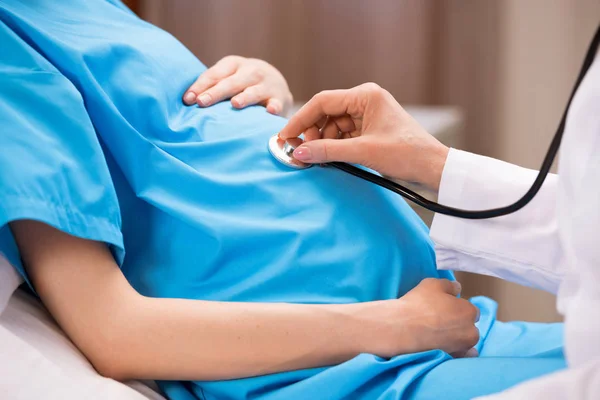 Doctor listening belly of pregnant woman — Stock Photo, Image