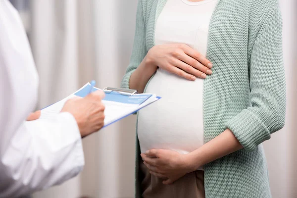 Врач с беременной женщиной во время консультации — стоковое фото