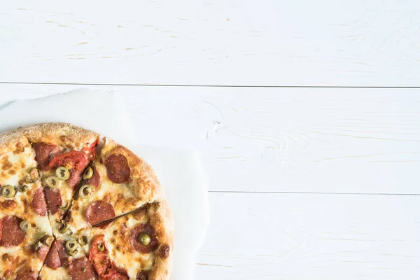 Italian pizza on baking paper — Stock Photo, Image