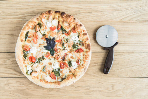 italian pizza with cutter on wooden tabletop