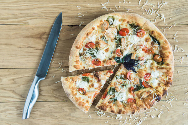italian pizza with knife on wooden tabletop