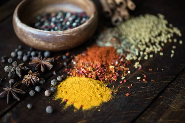 Pepper in bowl and spices with herbs on tabletop — Stock Photo, Image