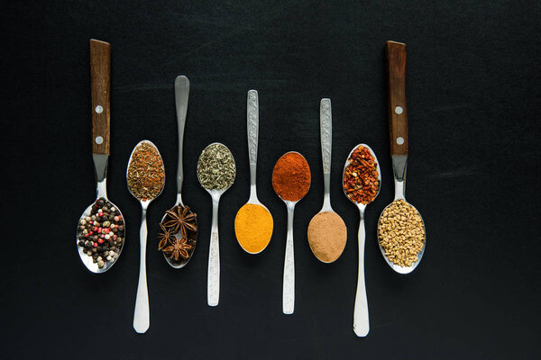 various spices and herbs in metal spoons