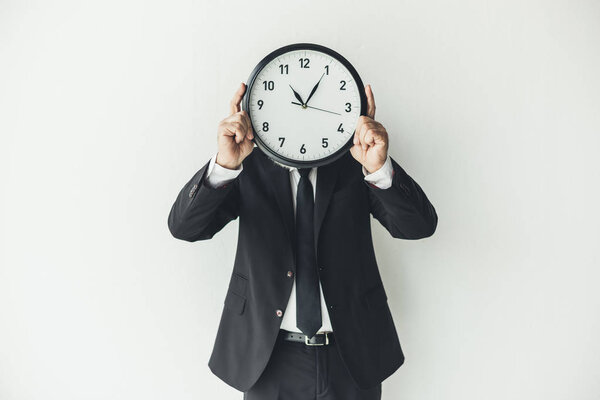 man covering face with clock