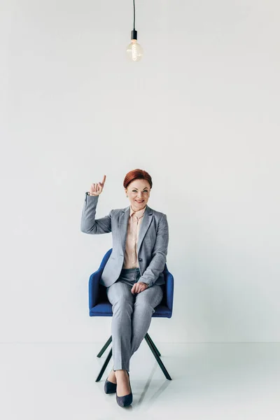 Businesswoman pointing at light bulb — Stock Photo, Image