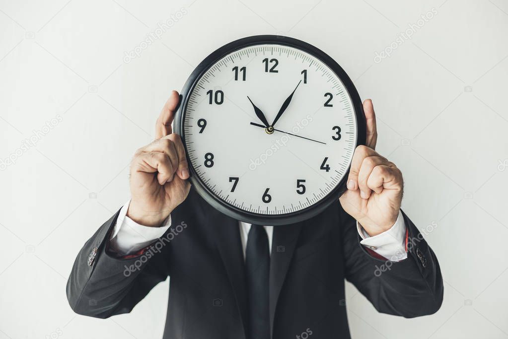 man covering face with clock