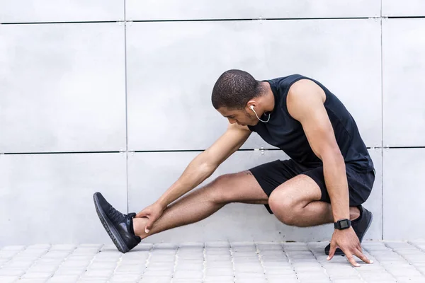 Afro-Amerikaanse sportman die zich uitstrekt op straat — Stockfoto