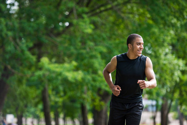 Африканский американский спортсмен бегает в парке
