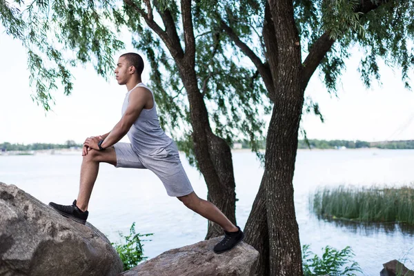 Afroamerikanska sportsman stretching på riverside — Stockfoto